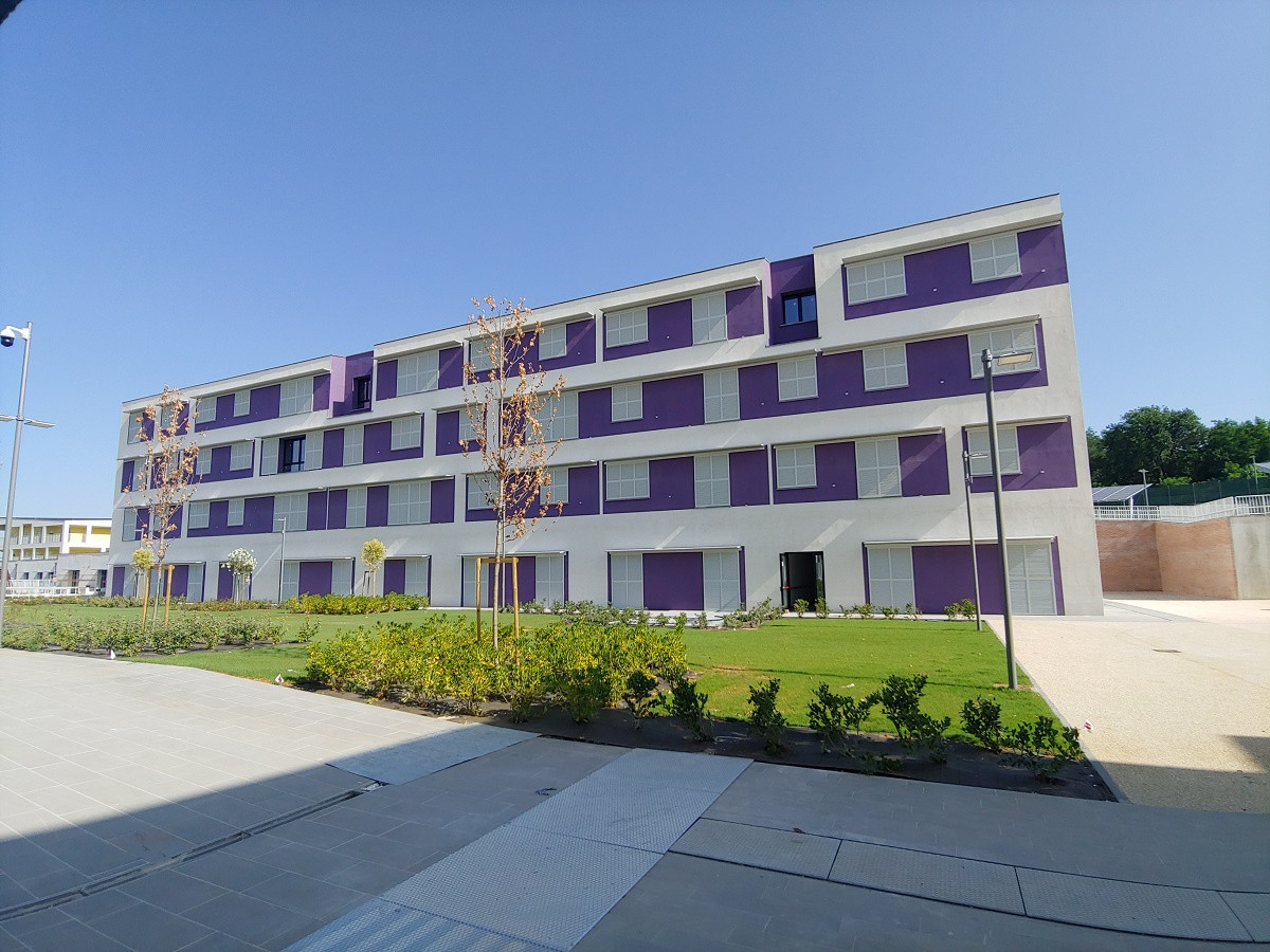 Vista dell'esterno dell'Edificio 5 - Residenze e Servizi educativi riabilitativi. Palazzina di colore viola con tapparelle/persiane bianche.