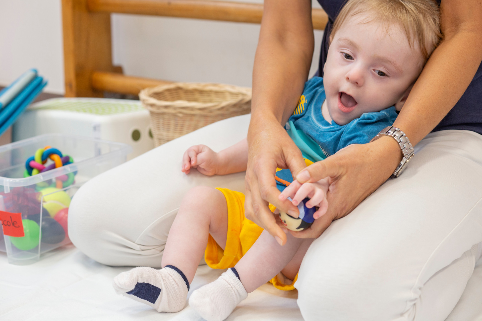 Gabriele, piccolo utente del Centro di Osimo, è sorretto dalla fisioterapista mentre si esercita a tenere in mano una pallina