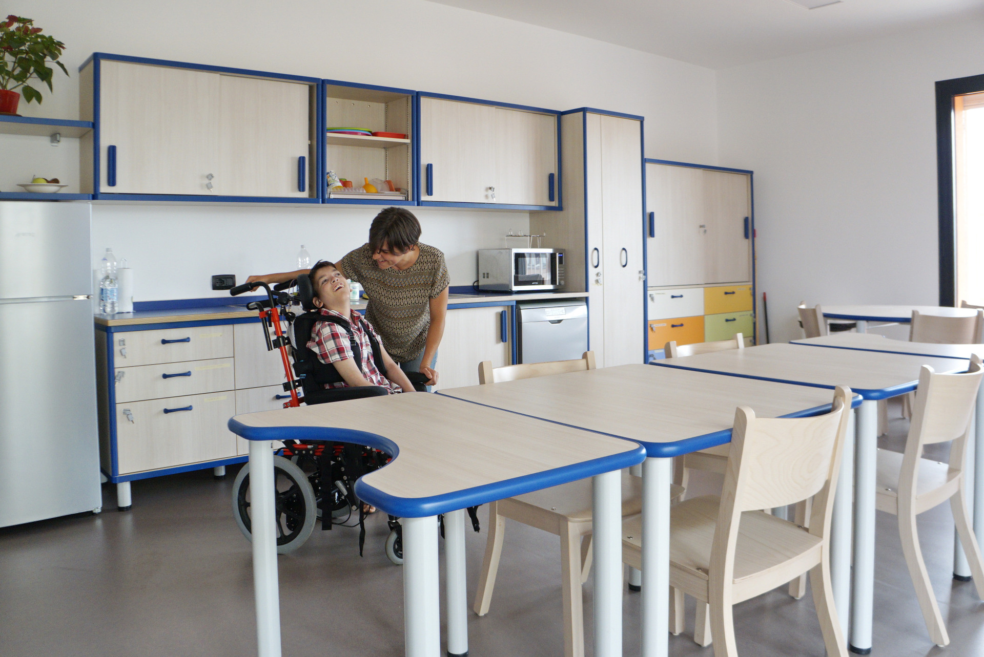 Mirko, ragazzino utente del Centro di Osimo, è nella cucina del suo appartamento insieme alla sua educatrice. L'ambiente è ampio e luminoso, con tavoli accessibili e una parete attrezzata di tutti gli elettrodomestici
