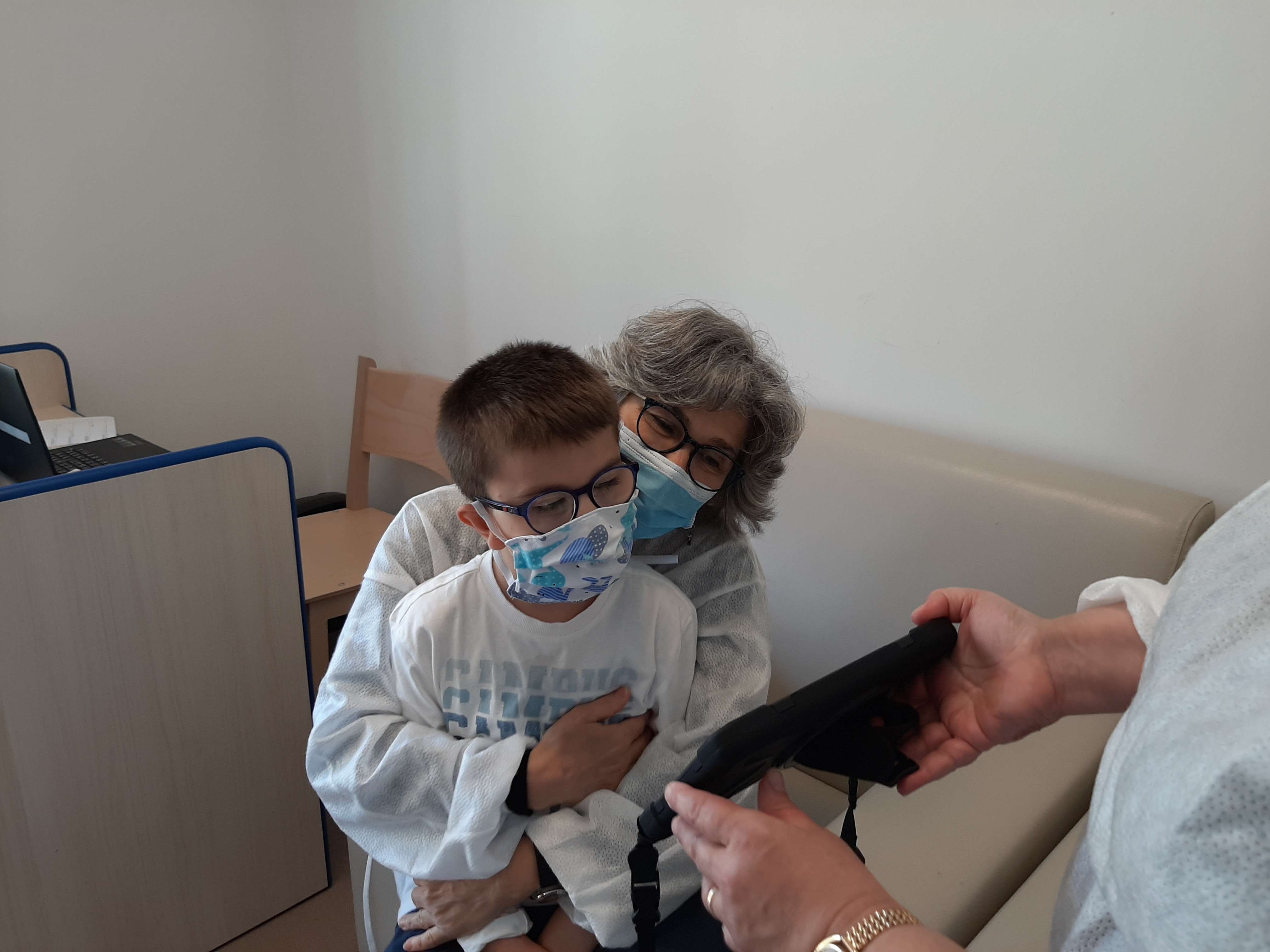 Una educatrice con camice monouso e mascherina tiene in braccio il piccolo Biagio mentre fanno una videochiamata con i genitori, durante il lockdown del 2020