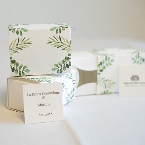 3 bomboniere in cartoncino bianco, decorate da un motivo verde a foglie. Accompagnate da un bigliettino personalizzato di esempio, con scritto "La prima Comunione di Martina" e la data 58
