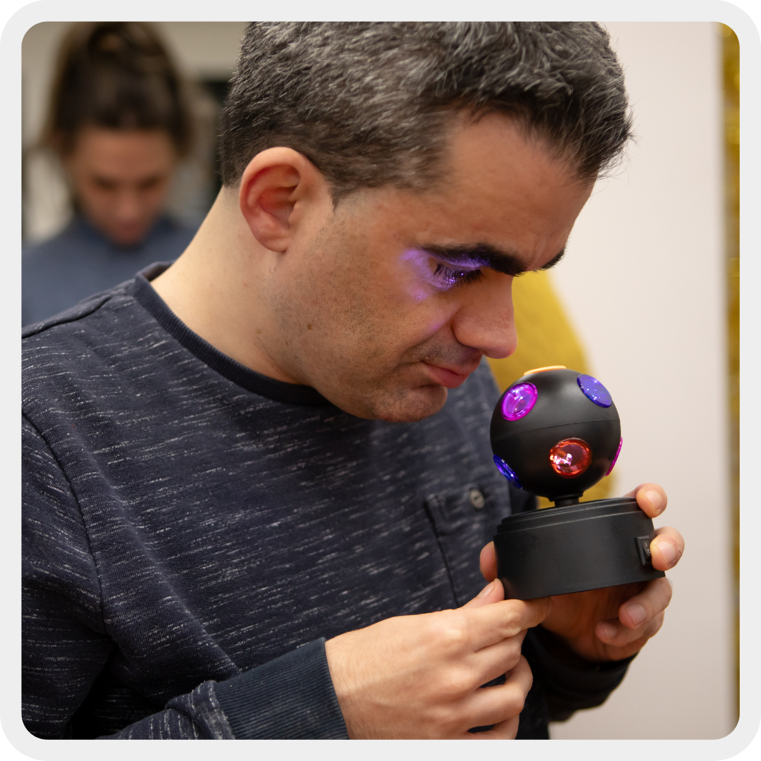 Nella foto, un utente del Centro Diurno del Centro Nazionale della Lega del Filo d'Oro, ha un residuo visivo che riesce a vedere le luci del gioco che tiene in mano.