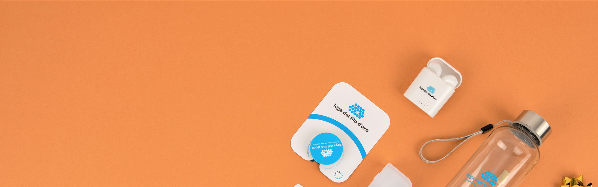 Composizione di regali solidali su sfondo arancione, inclusi auricolari, pop grip, chiavetta USB, borraccia in tritan e braccialetto Cruciani. Perfetti per donare con stile e solidarietà.