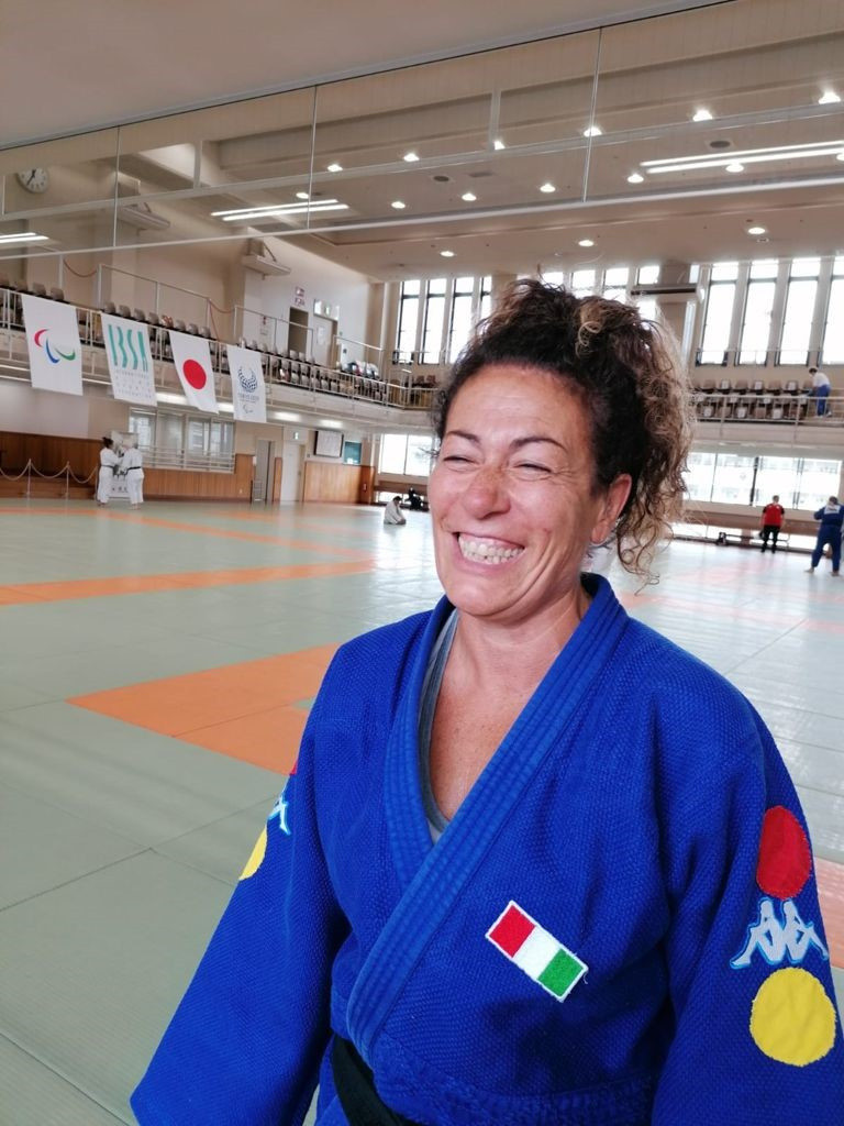Foto di Matilde, judoka sordocieca, con indosso il judodi della nazionale con i due cerchi, rosso e giallo, che indicano le doppia disabilità. Lo sguardo è frontale, Matilde sorride.
