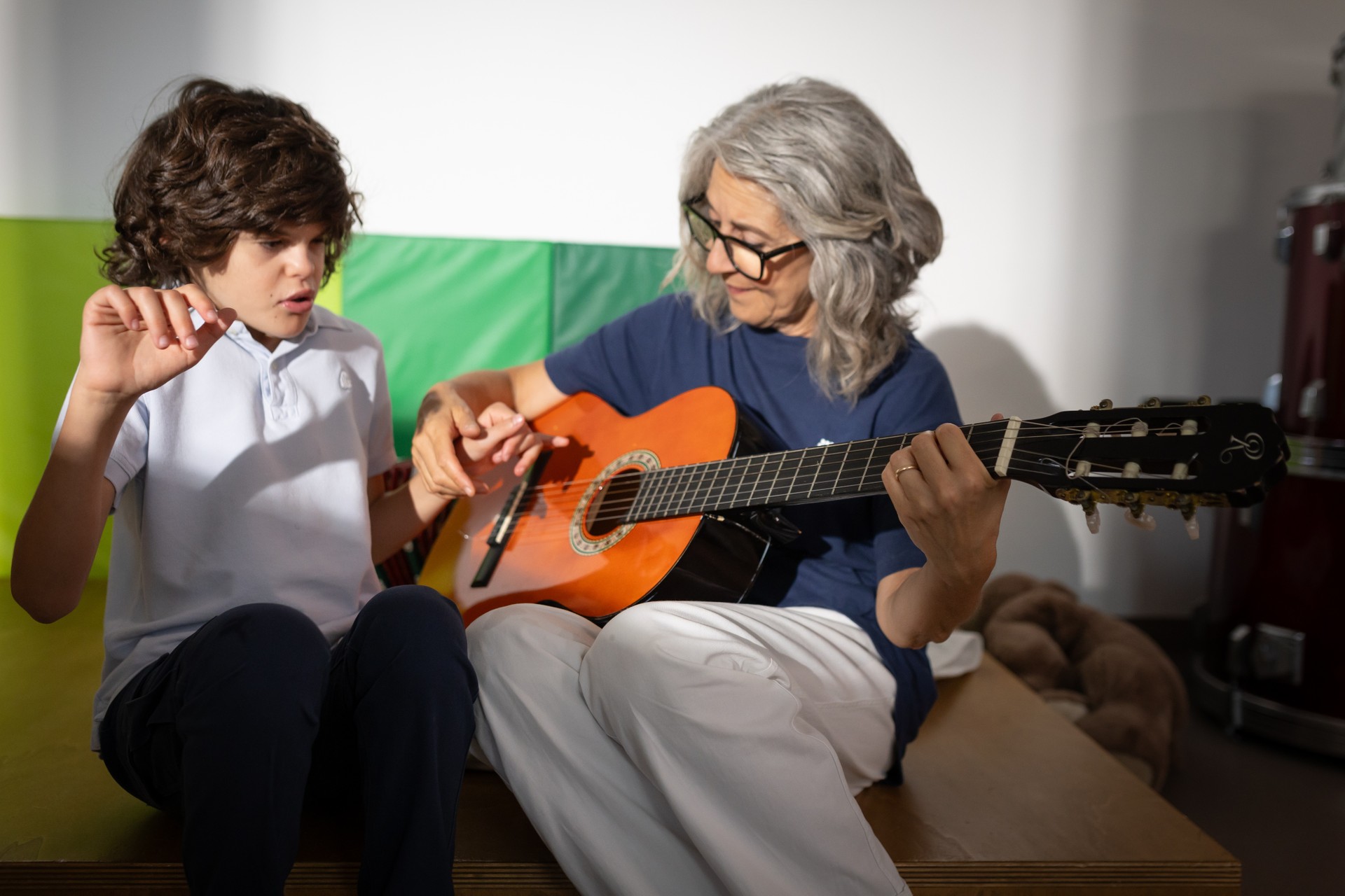 L'educatrice di musicoterapia di Agostino lo aiuta a suonare la chitarra