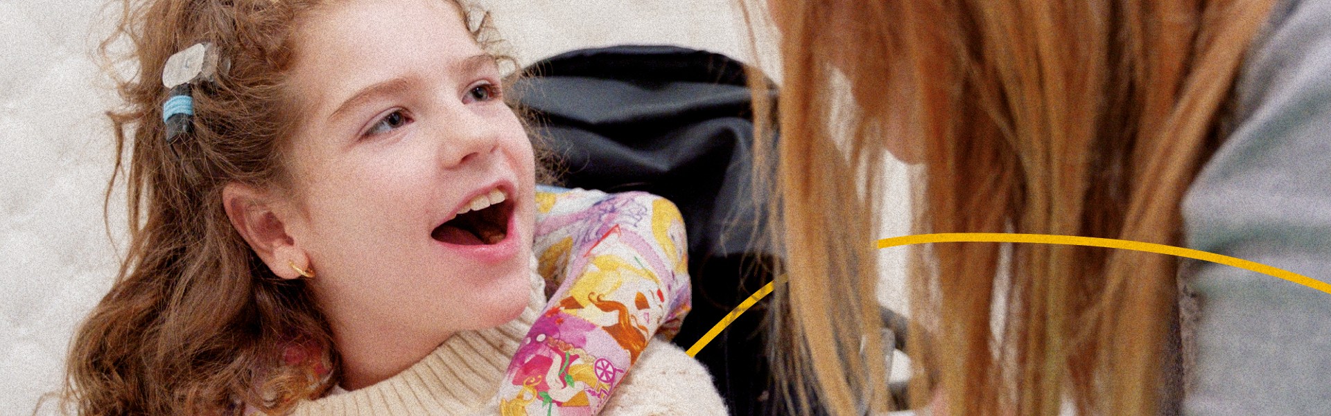 Bambina insieme a un’operatrice in primo piano. Immagine che evidenzia relazione, cura e vicinanza in un contesto educativo inclusivo della Lega del Filo d’Oro.