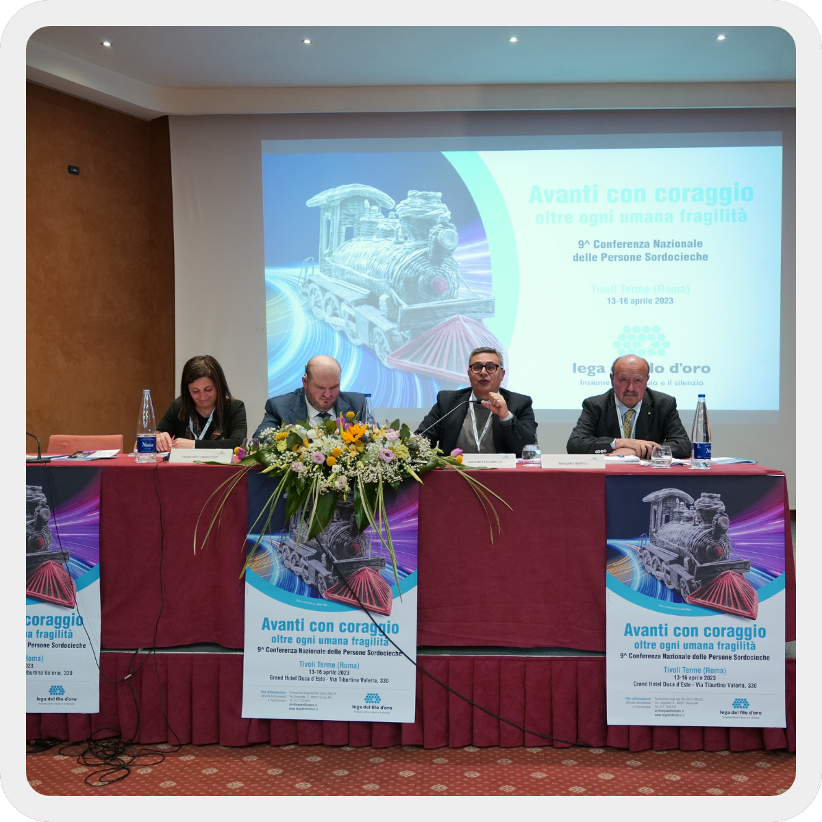 Al tavolo dei relatori della Conferenza Nazionale delle Persone sordocieche dalla sx: Cinzia Acquaroli, operatore territoriale di Osimo; Francesco Mercurio, Presidente Comitato Persone Sordocieche; VIncenzo Falabella, Presidente FISH; Rossano Bartoli, Presidente Lega del Filo d'ORo. Lungo il tavolo e dietro i relatori i manifesti della Conferenza che ne riportano il titolo "Avanti con Coraggio oltre ogni umana fragilità"