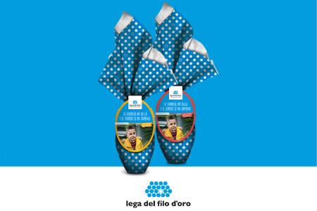 Due uova di Paqua, su uno sfondo azzurro con una fascia bianca in basso. Le uova sono incartate con carta azzurra a pois bianchi.