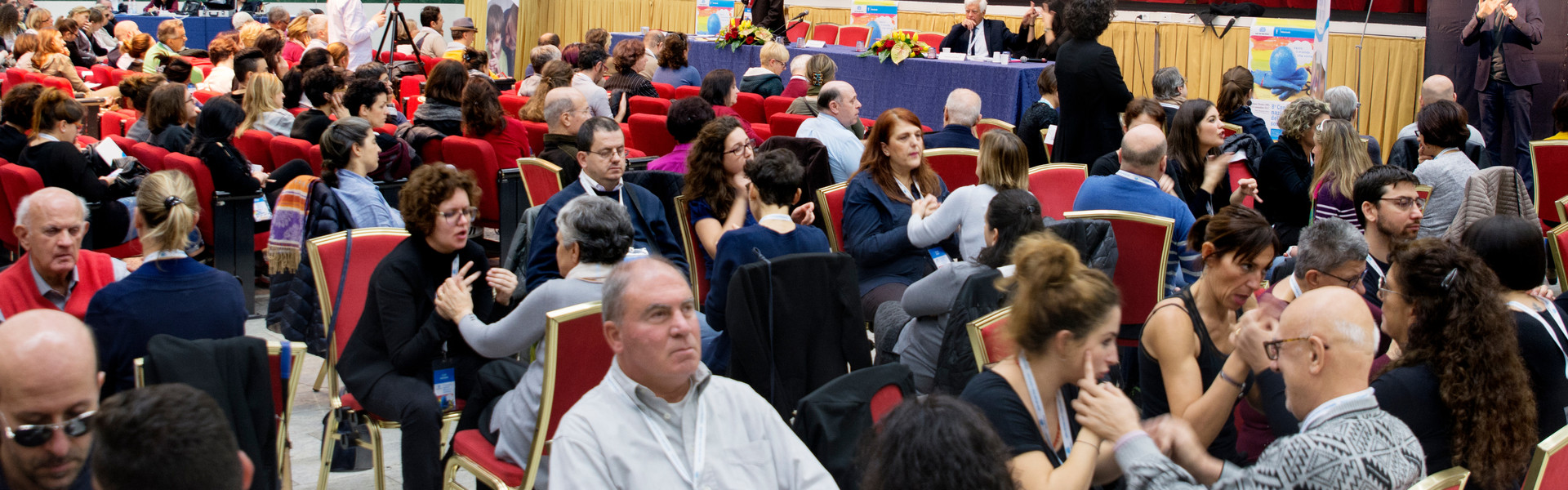Conferenza nazionale delle persone sordocieche anno 2018. vista della platea. tante persone sordocieche e interpreti comunicano tra loro in LIS tattile e Malossi