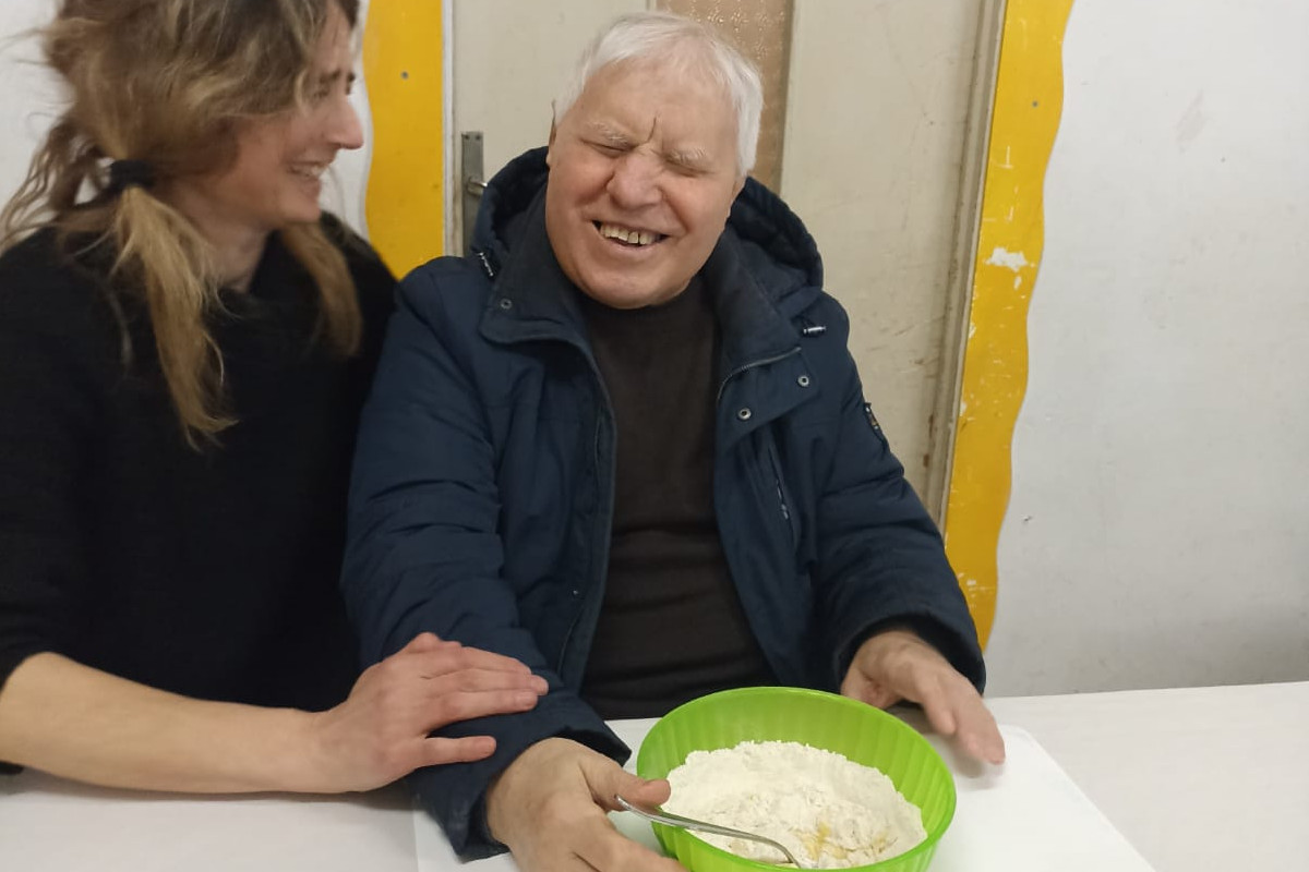 Un utente della Lega del Filo d’Oro e una volontaria sono ritratti mentre preparano l’impasto per le tagliatelle.