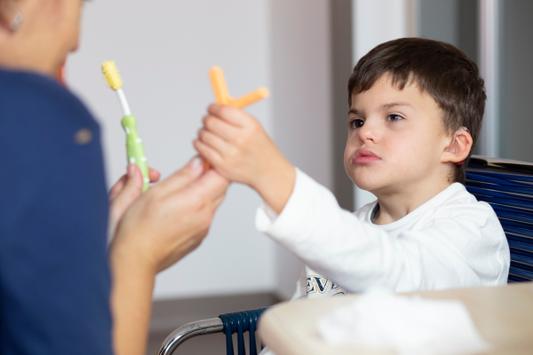Agostino, bambino seguito al Centro di Osimo, sceglie uno dei due oggetti che l'educatrice gli sta mostrando per la sua prossima attività