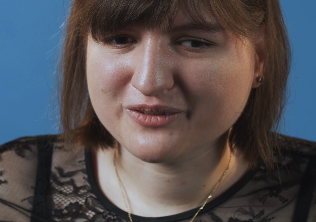 Foto in primo piano di Giona durante le riprese di un video. E' vestita elegantemente di nero e sorride.