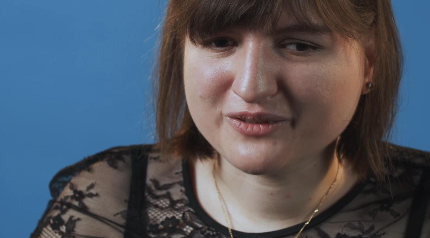 Foto in primo piano di Giona durante le riprese di un video. E' vestita elegantemente di nero e sorride. 