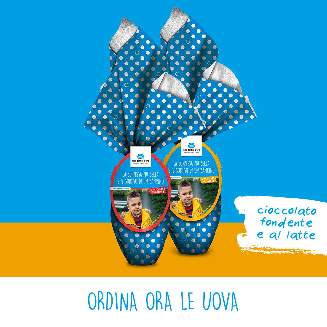 Su uno sfondo colorato azzurro e arancione, ci sono due uova di pasqua. Confezionate con una carta a pois azzurra e bianca, sono una al latte e l'altra al cioccolato.