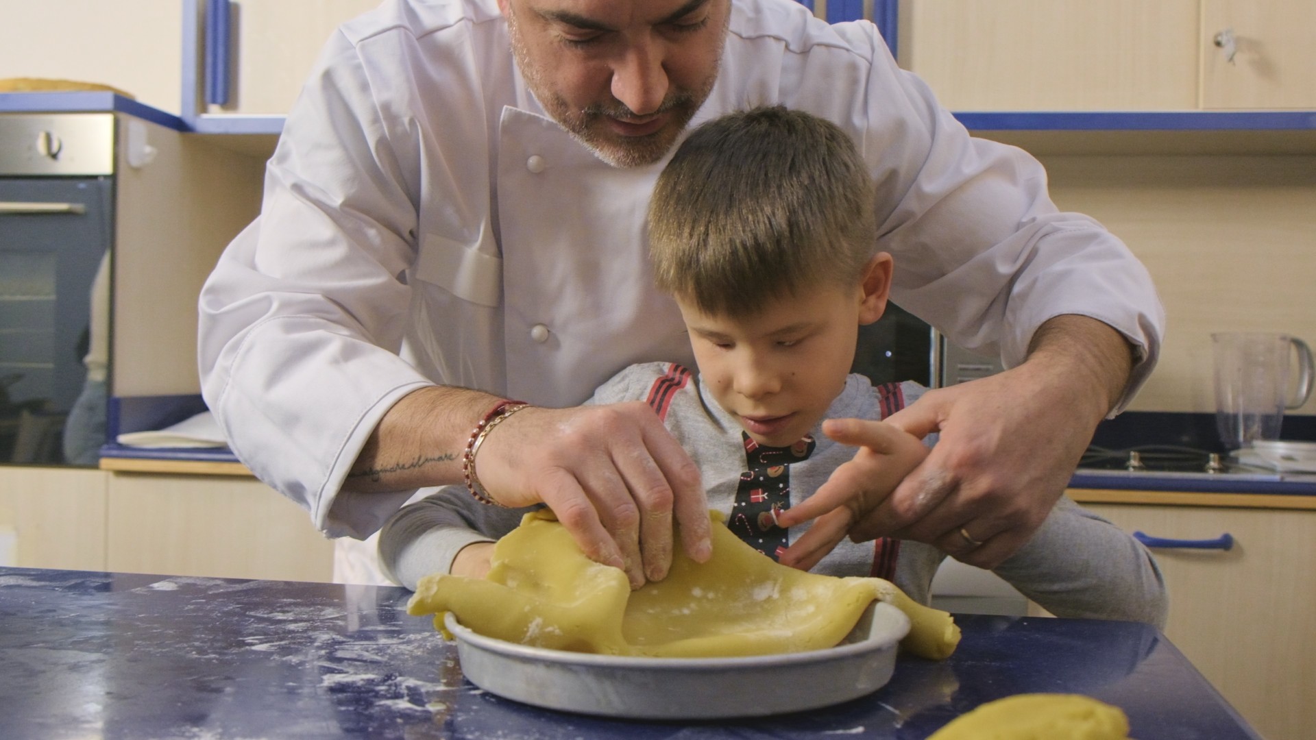 Un pasticcere nella cucina didattica (presso il Centro Nazionale della Lega del Filo d'Oro) con Matteo stanno preparando la pasta sfoglia per la torta con la panna montata.