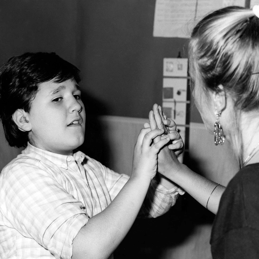 Un bambino sordocieco comunica tramite il tocco della mano con una donna. Immagine degli anni '80 in bianco e nero.