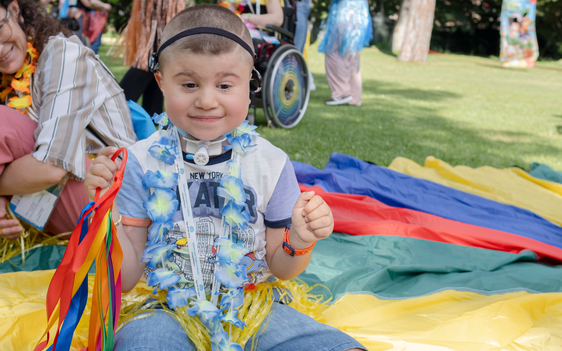 Berkay, bambino seguito dalla Lega del Filo d'Oro con sindrome Charge, ripreso mentre gioca in giardino su tappetoni colorati all'Assemblea delle Famiglie ad Assisi
