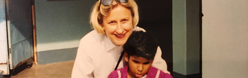 Foto di Anna che abbraccia sorridendo sua figlia Rekha. La bambina (circa 7 anni nella foto, utente Lega del Filo d'Oro) tiene in mano un bastone bianco per non vedenti