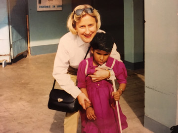 Foto di Anna che abbraccia sorridendo sua figlia Rekha. La bambina (circa 7 anni nella foto, utente Lega del Filo d'Oro) tiene in mano un bastone bianco per non vedenti