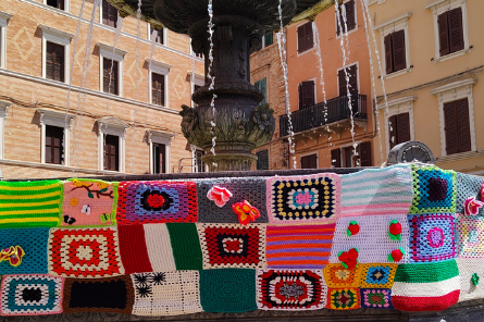 Fontana nella piazza di Osimo decorata con grandi tasselli colorati, tra cui la bandiera italiana, realizzata per lo Yarrn Bombing