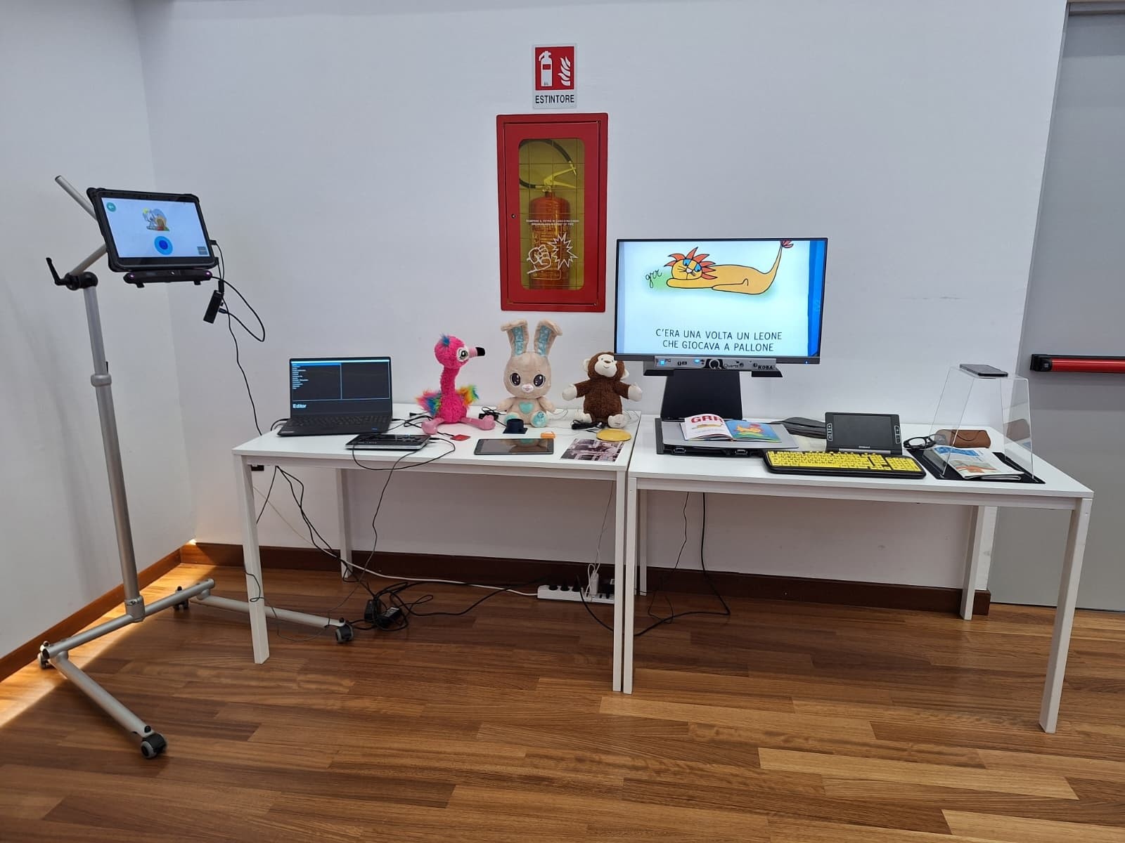 Esposizione di tecnologie assistive allestita durante il convegno "Il bambino con malattia rara e disabilità: dalla diagnosi all’assistenza". Su tavoli sono presentati dispositivi per la comunicazione, strumenti digitali e materiali accessibili pensati per favorire partecipazione, autonomia ed espressione delle persone con disabilità.