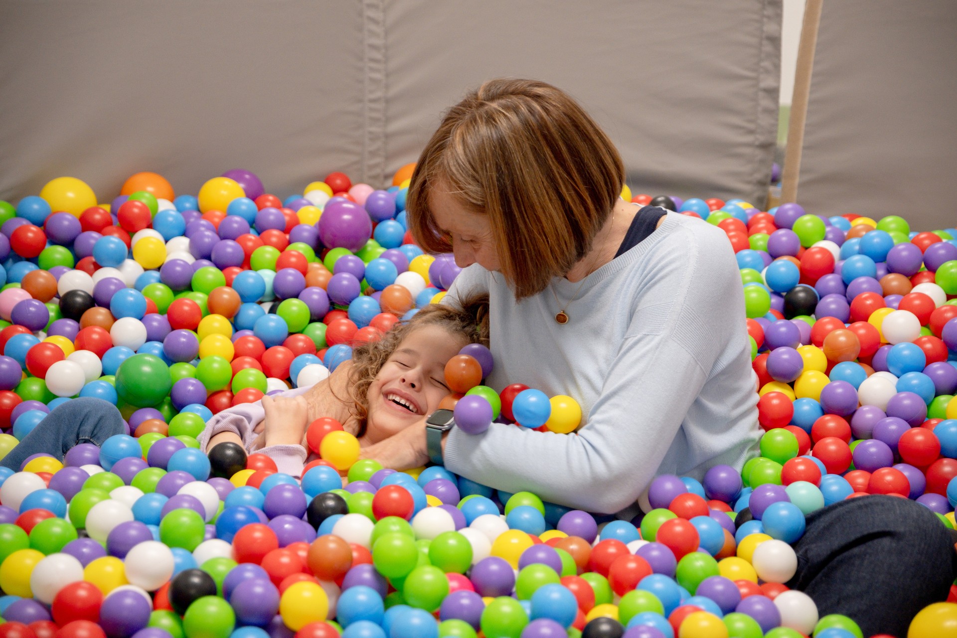 Chiara è insieme alla sua educatrice. E' nella vasca delle palline colorate: sta ridendo ed è quasi completamente sommersa dalle palline.