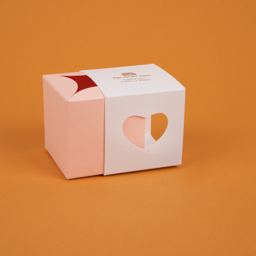 Bomboniera composta da due scatoline in cartoncino pregiato inserite l'una nell'altra. Quella esterna è bianca, quella interna, visibile da un'apertura a forma di cuore, è rosa 47