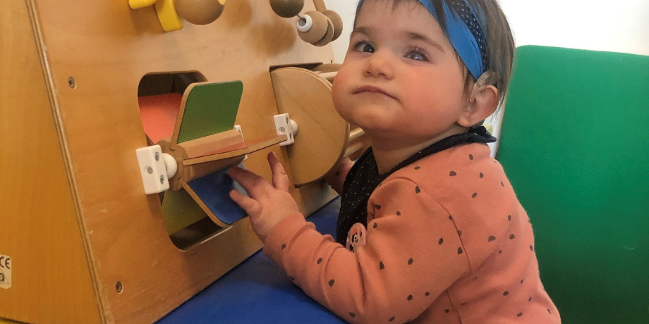 La piccola Letizia, bambina con la sindrome di Charge, qui aveva circa un anno. Una piccola bambina dalle guanciotte tonde, i capelli corti, mentre gioca.