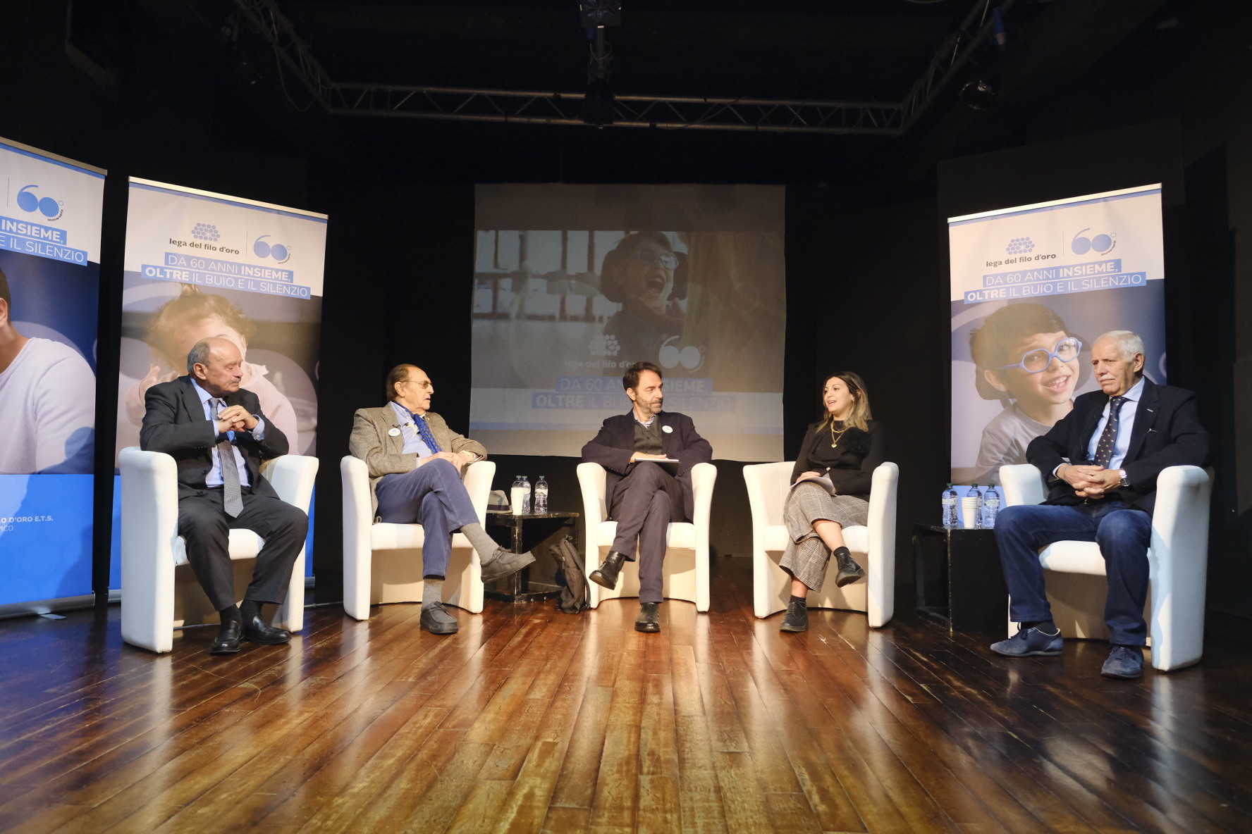 Evento lancio campagna del 60° anniversario. In sala sono seduti i testimonial Neri Marcorè e Renzo Arbore, il Presidente della Lega del Filo d'Oro Rossano Bartoli, la mamma di Nicola, Paola e uno dei sostenitori storici della Lega del Filo d'Oro, Ambrogio, uno dei protagonista della campagna.
