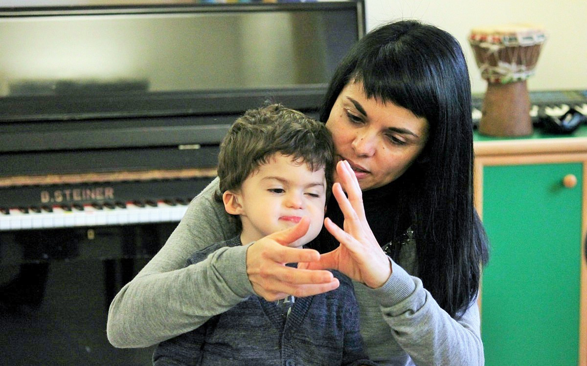 Mamma Samuela tiene in braccio Agostino, bambino seguito dalla Lega del Filo d'Oro, e gli "canta" una filastrocca aiutandosi con la LIS