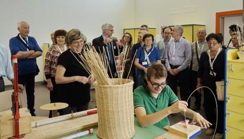 Un gruppo di sostenitori in visita al nuovo Centro Nazionale di Osimo della Lega del Filo d'Oro in occasione della Giornata del Sostenitore osservano Victor che lavora il midollino nel laboratorio