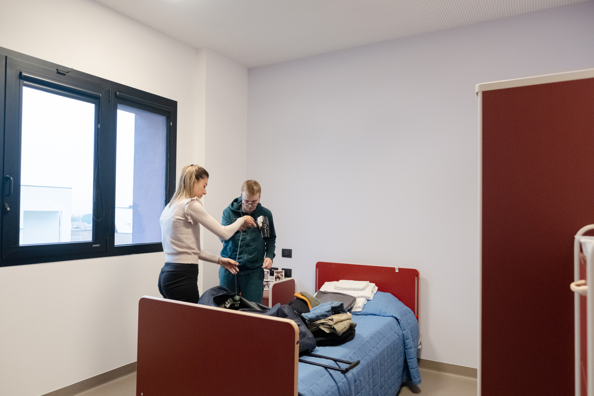 Victor, ragazzo residenziale del Centro Nazionale di Osimo, insieme all'operatrice disfa le valigie nella sua nuova camera