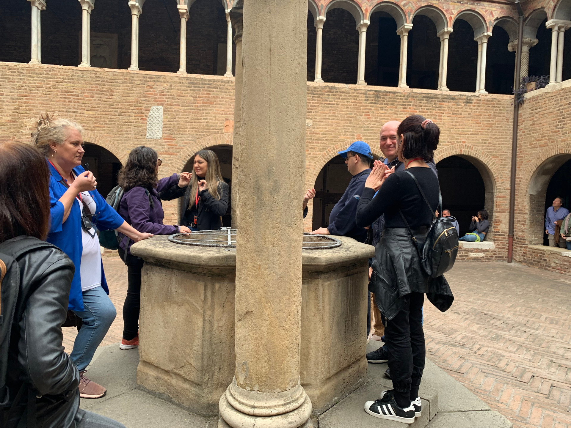 Un'immagine che mostra utenti che chiacchierano di fronte a un antico pozzo di marmo, creando un'atmosfera di socializzazione e scoperta.