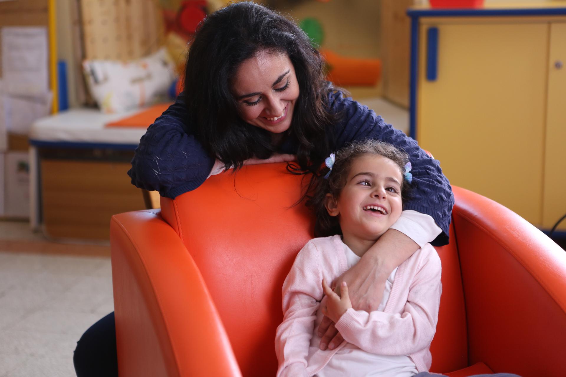Una bimba sordocieca di nome Sofia e sua mamma giocano sorridenti.