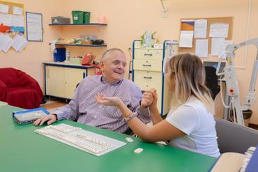 Fabio, residente al Centro Nazionale di Osimo, gioca a domino con la sua educatrice divertendosi e ridendo