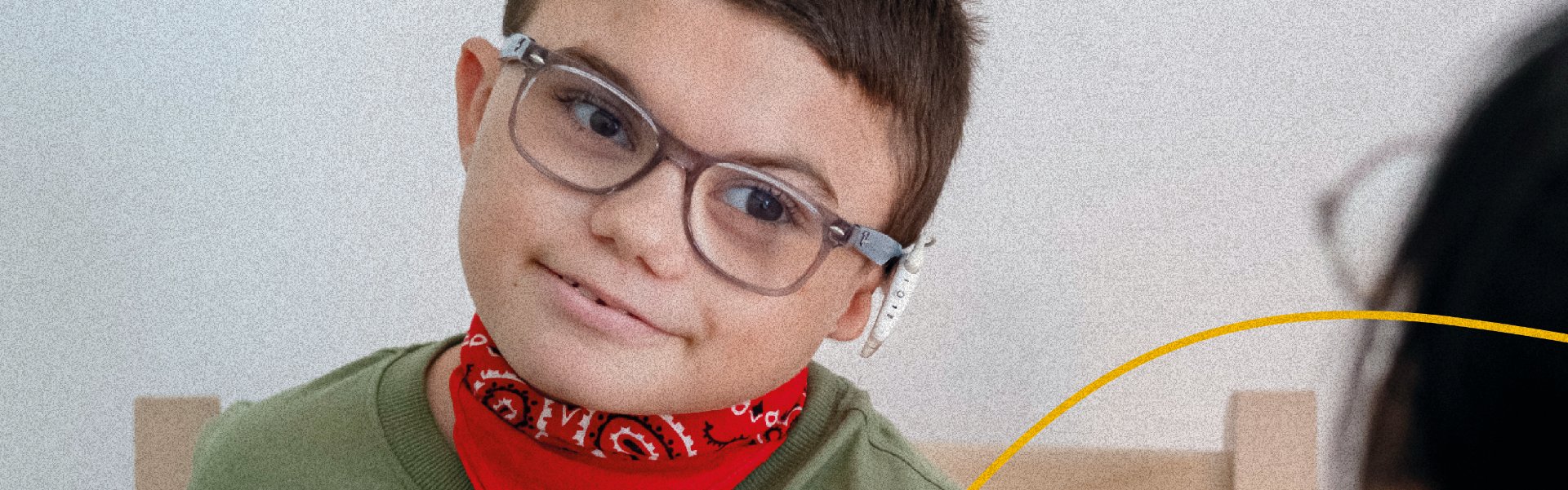 Leonardo, bambino della Lega del Filo d’Oro, sorride in primo piano.