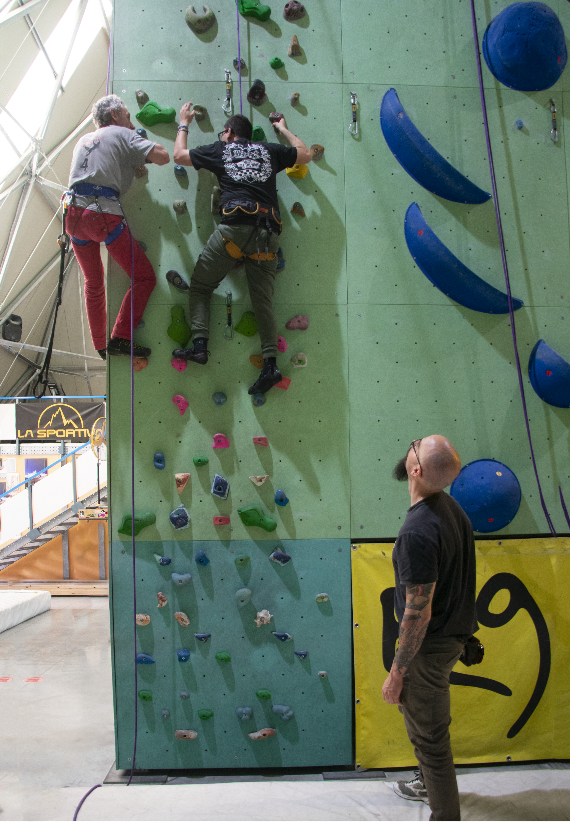 Un gruppo di persone seguite dal Servizio Territoriale di Osimo ha recentemente partecipato ad una giornata di arrampicata, con l'obiettivo di andare oltre le barriere sensoriali, sviluppare fiducia in sé stessi e socializzare. Un utente, in totale sicurezza grazie all’imbracatura, affronta una parete da arrampicata indoor. Accanto a lei, un membro dello staff la assiste con attenzione.