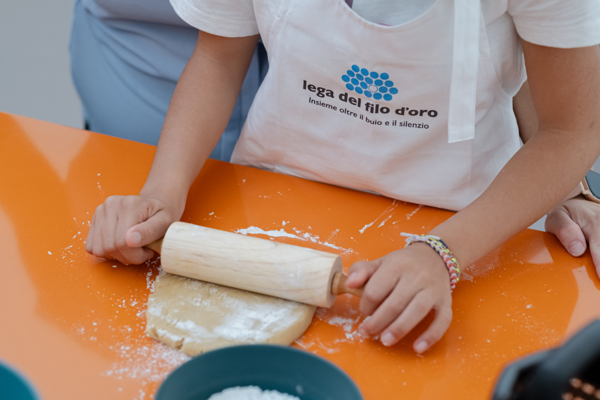Le mani di Aida, bambina seguita dalla Lega del Filo d'Oro, mentre tira con il mattarello l'impasto per fare i biscotti. È attivo da nove anni il programma “Alimentiamo la vita insieme”, cuore della partnership tra la Società Cooperativa Agroalimentare TreValli Cooperlat e la Fondazione Lega del Filo d’Oro.
