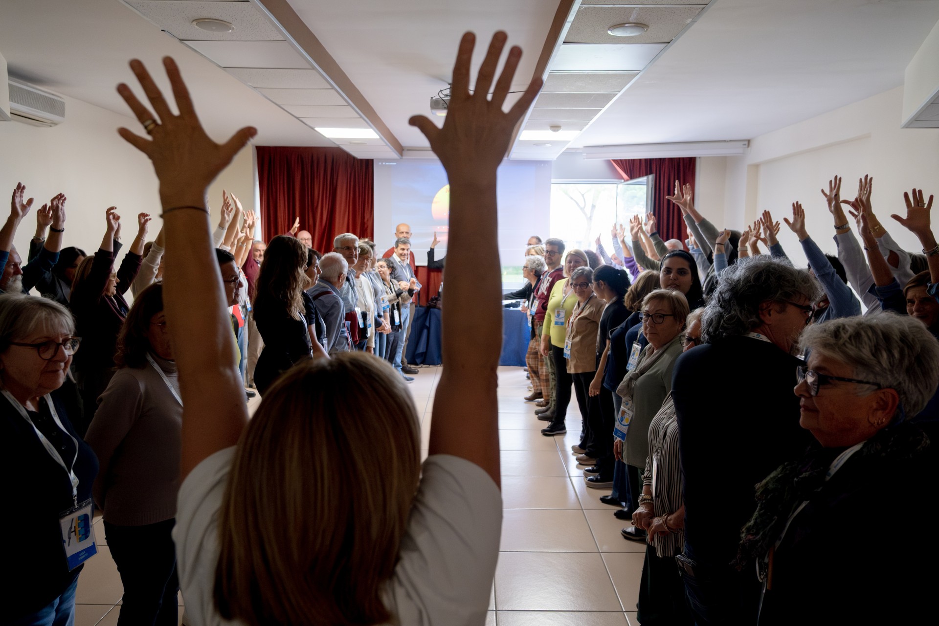 Durante il laboratorio di musica del Forum dei Volontari, i partecipanti alzano le mani con entusiasmo e sorridono. Un momento di gioia, condivisione e partecipazione che valorizza inclusione e coinvolgimento di tutti.