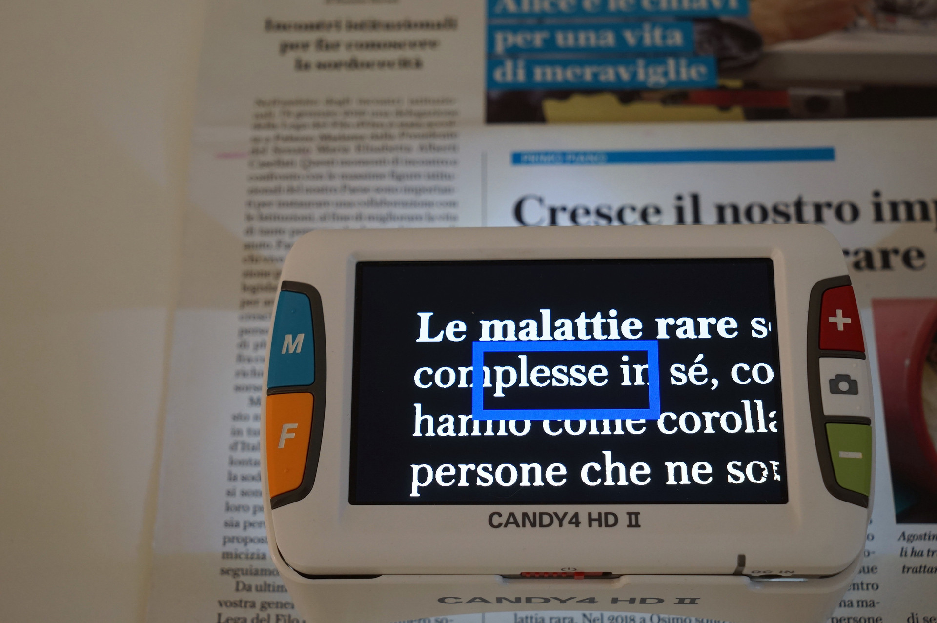 Un video ingranditore è poggiato su un numero di Trilli nell'Azzurro, il notiziario della Lega del Filo d'Oro. Sullo schermo, il testo degli articoli risulta ingrandito e il contrasto adattato per facilitare la lettura a persone con residuo visivo
