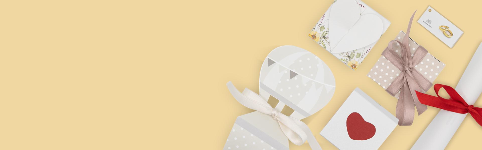 Composizione di bomboniere per anniversario su sfondo giallo, con bomboniera a forma di cuore, bomboniera evergreen e bomboniera pergamena, perfette per celebrare occasioni speciali con eleganza e stile.