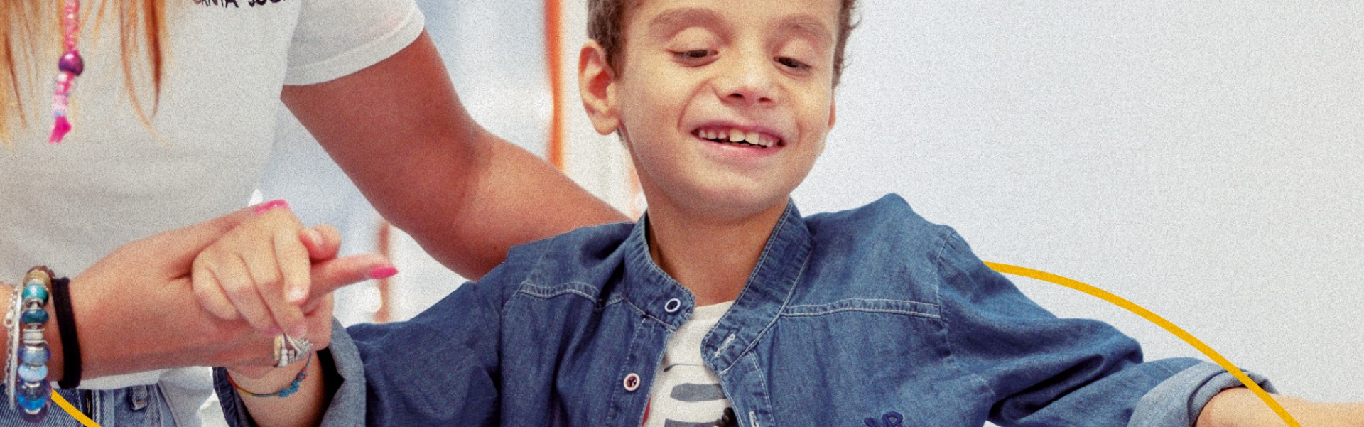 Bambino utente della Lega del Filo d’Oro cammina mano nella mano con un’operatrice.