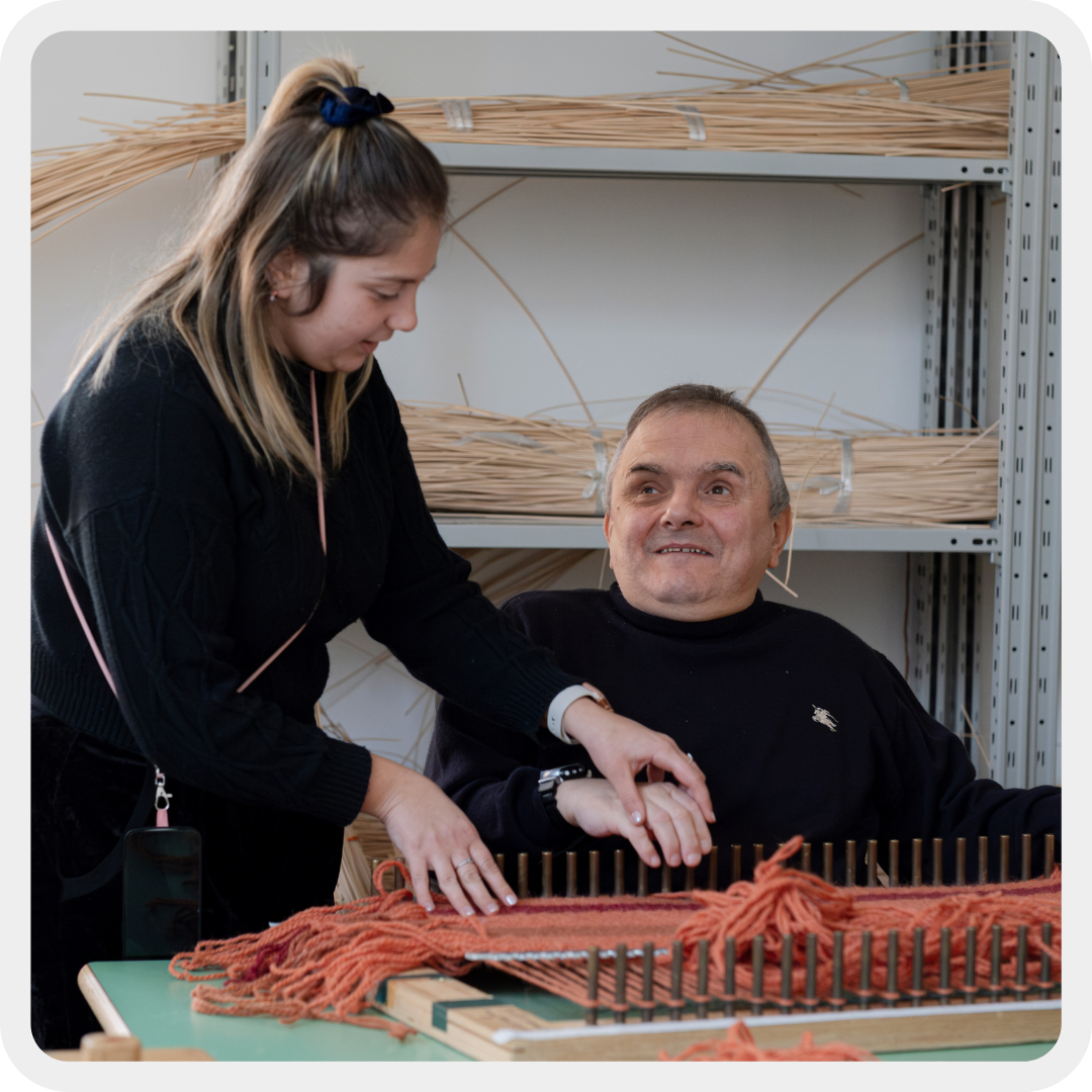 Fabio, utente residenziale del Centro Nazionale di Osimo, è nel laboratorio di cestineria del Centro insieme alla sua operatrice alice mentre sono al telaio.