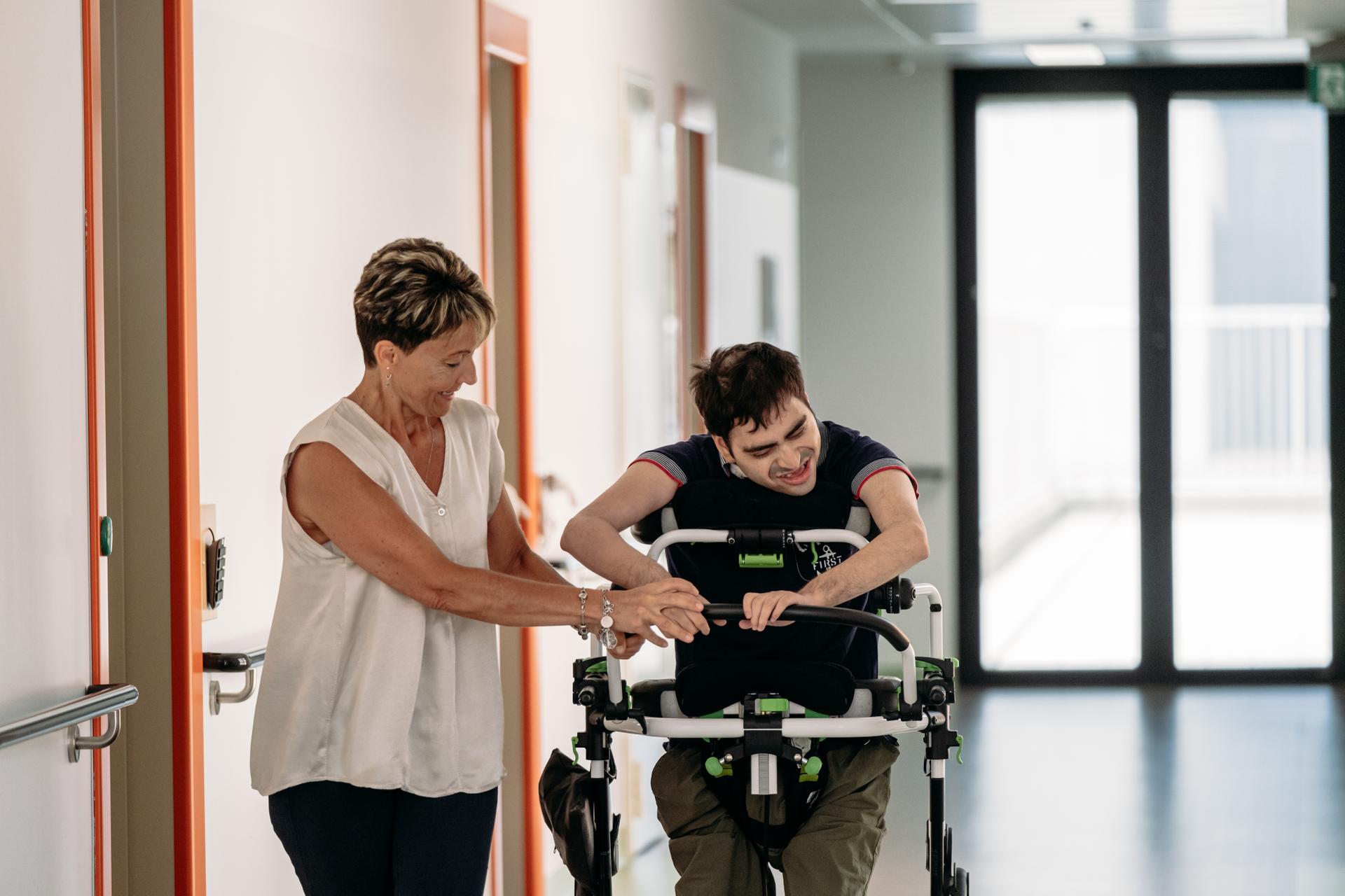 Simone, utente del Diurno al Centro Nazionale di Osimo, mentre passeggia con la sua educatrice, Sonia, nei corridoi del Centro