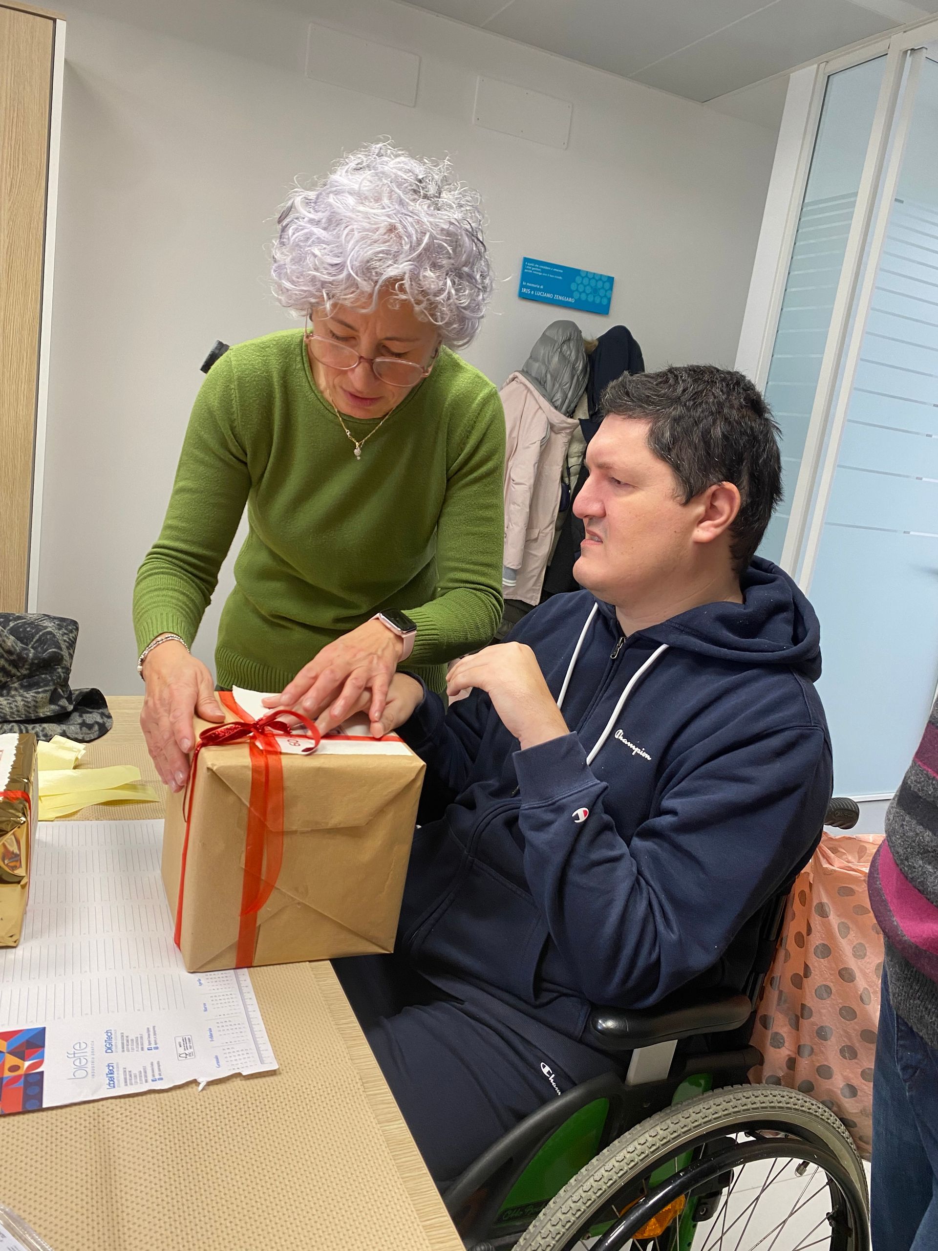 Un utente della Lega del Filo d'Oro ha ricevuto un regalo di Natale e lo apre insieme all'operatrice