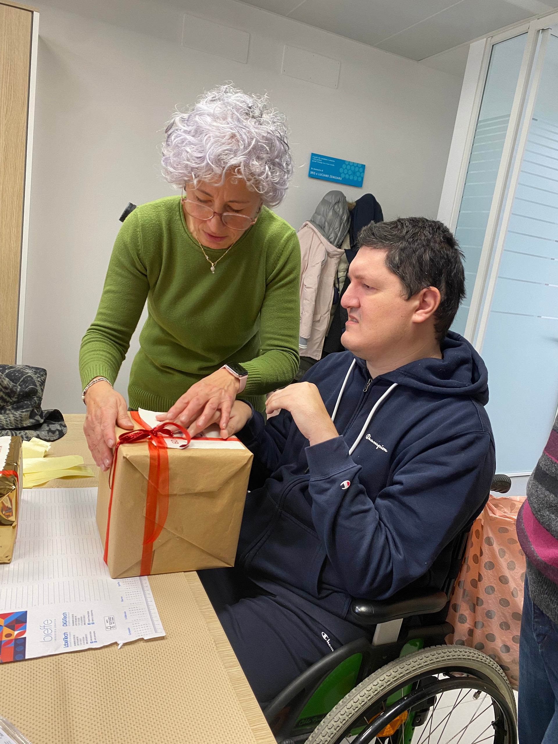 Un utente della Lega del Filo d'Oro ha ricevuto un regalo di Natale e lo apre insieme all'operatrice