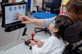 L'utente Nicola è sulla sua sedia a rotelle ed interagisce con il tablet che ha davanti grazie ad un controller particolare. E' supportato dalla sua educatrice
