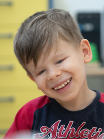 Un utente bambino della Lega del Filo d'Oro sorride in primo piano
