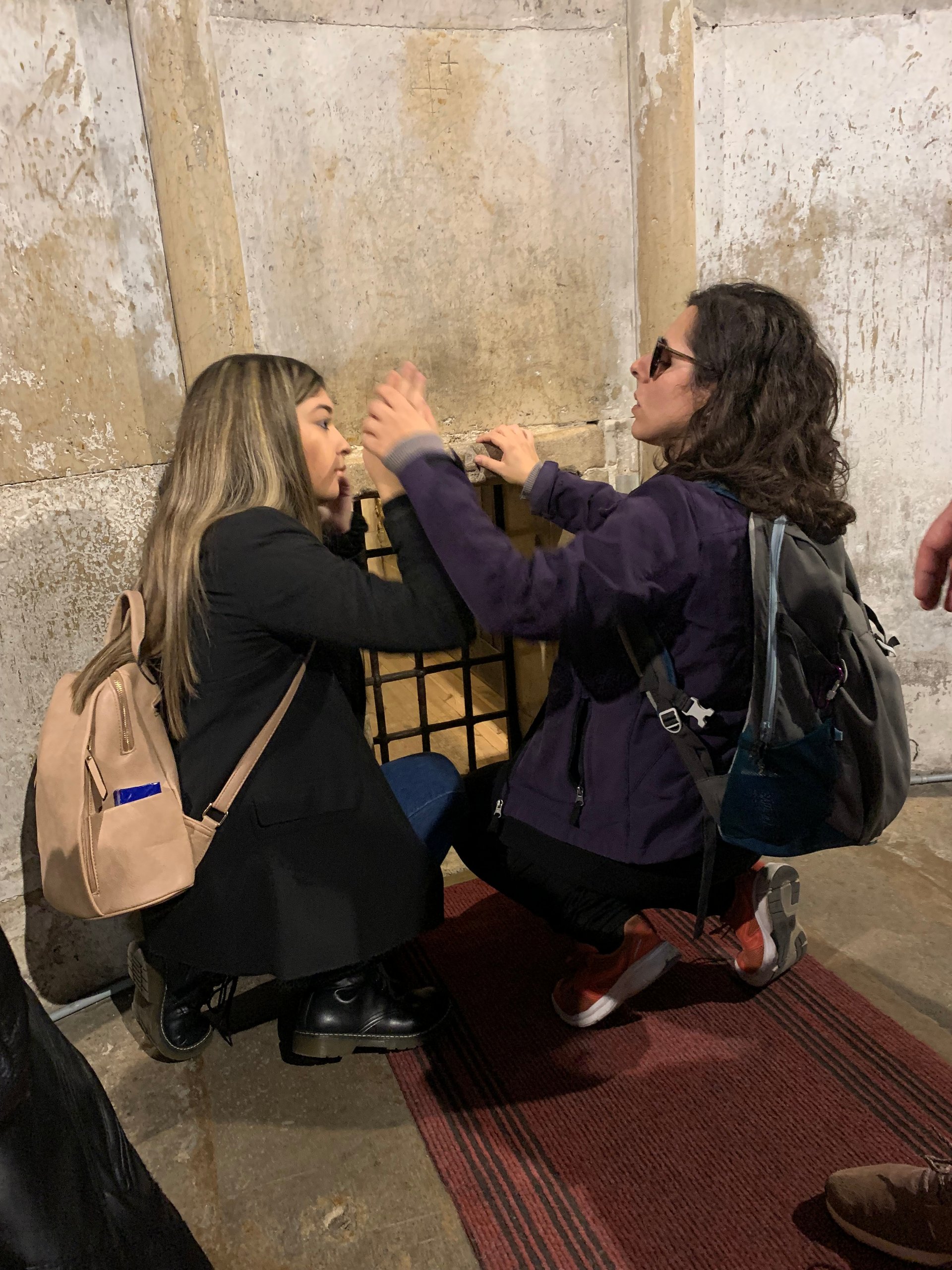 Un’utente tocca una grata in ferro, accompagnata da una volontaria che la guida nell’esplorazione tattile. 