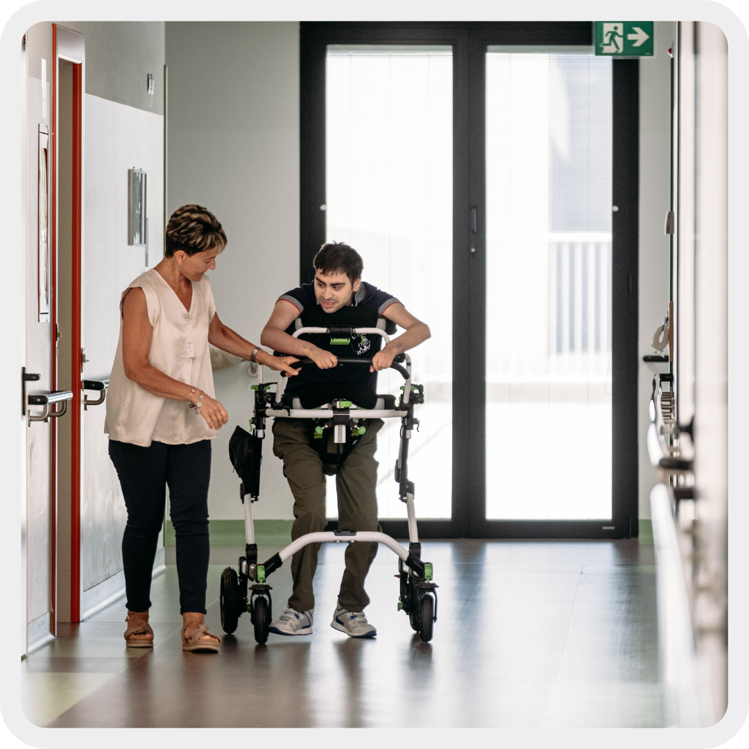 Simone, un ragazzo con gravi disabilità sensoriali e motorie, insieme alla sua educatrice nei corridoi del centro nazionale ad Osimo.